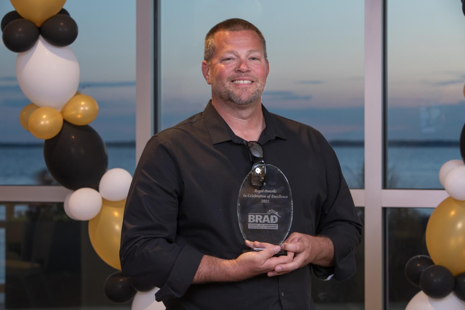 Chuck Coleman, Owner of Sea Light Design-Build, Holding a BRAD Award