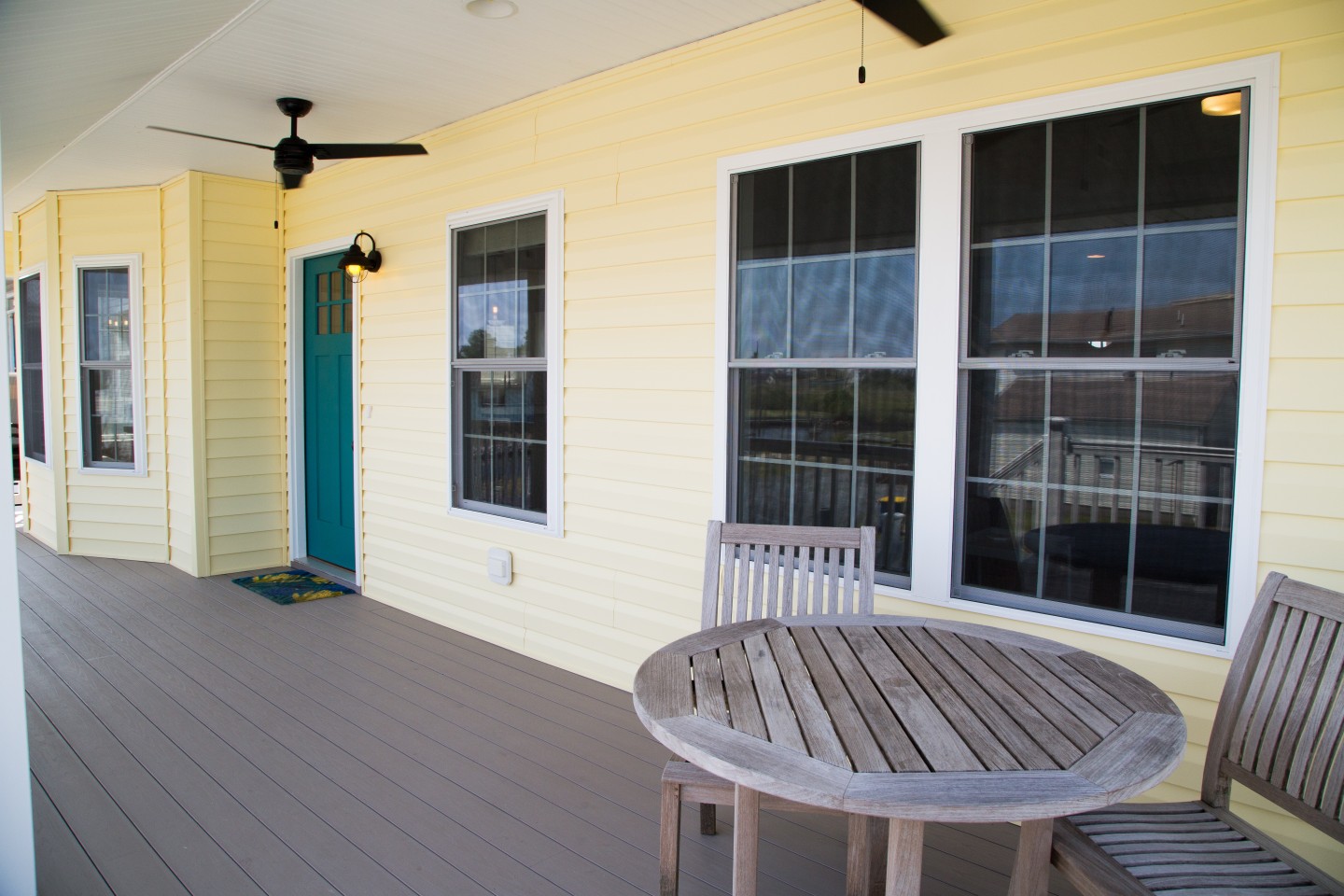 Exterior Porch with Yellow Siding, Wooden Round Table and Chairs