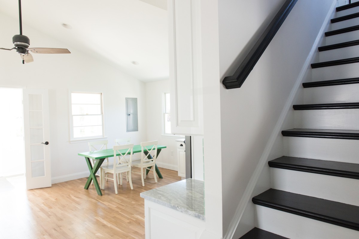 Kent Renovation Bethany Beach, DE Black and White Stairway with Black Railing, Green Dining Table and White Chairs