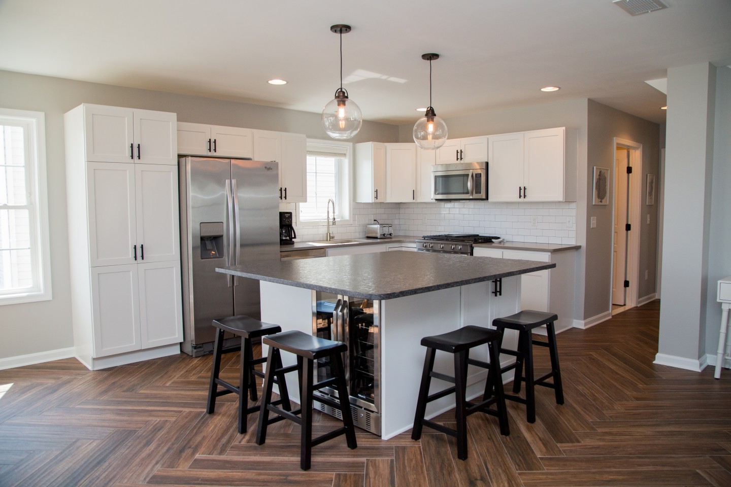 Contemporary Kitchen with White Cabinets, Dark Flooring and Center Isle