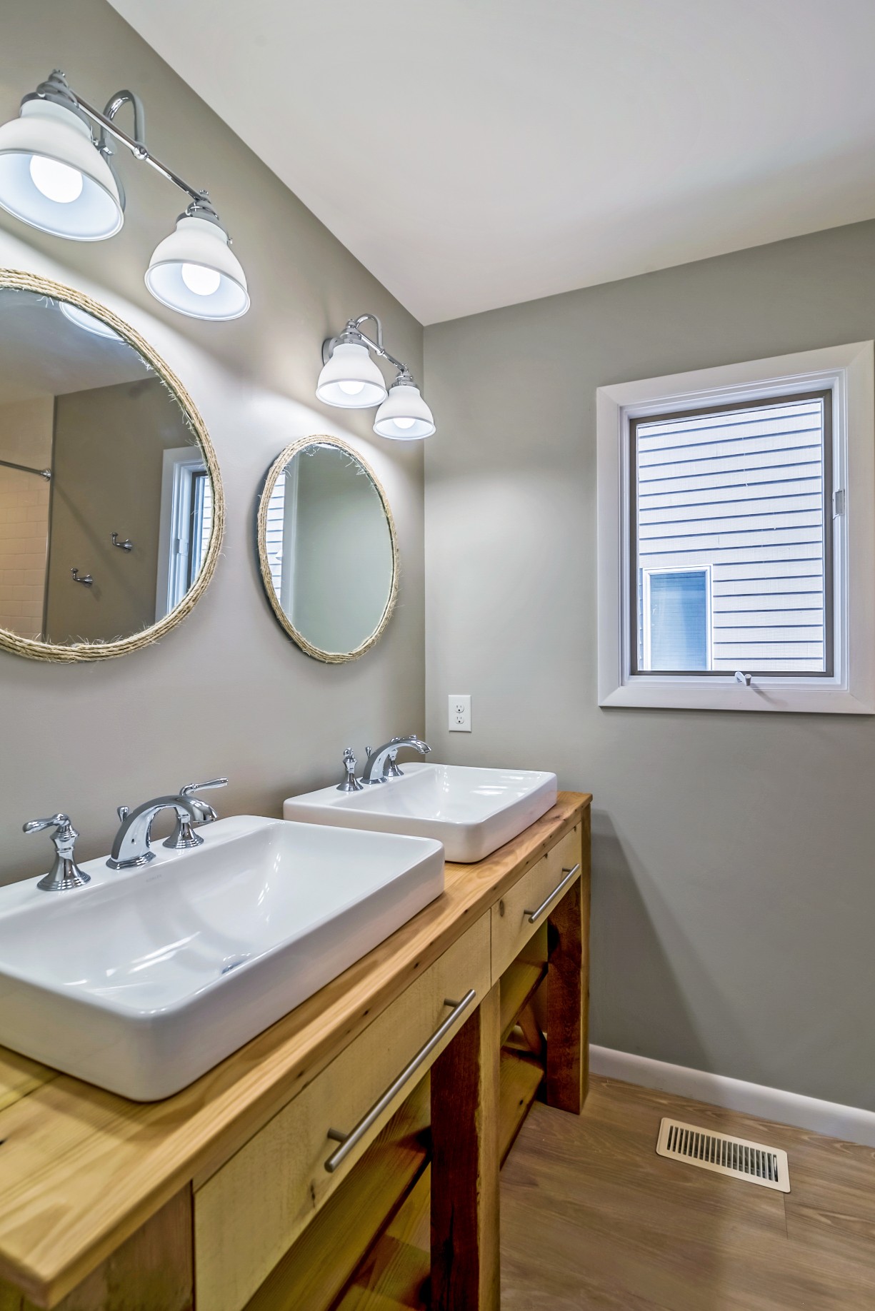 Bathroom Remodel in Wellington Parkway, Bethany Beach DE with Dual Sinks, Two Round Mirrors and Light Wood Vanities